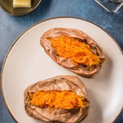 A brown rimmed plate with two cut open sweet potatoes and the words Air Fryer Baked Sweet Potatoes at the top.