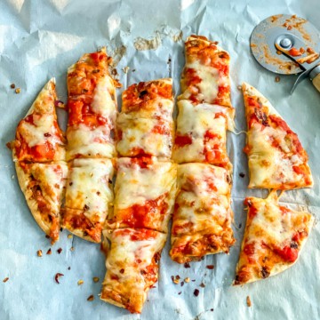 A small cheese pizza, cut into strips with a pizza cutter.