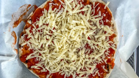 A naan bread pizza topped with shredded mozzarella cheese.