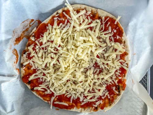 A naan bread pizza topped with shredded mozzarella cheese.