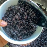 Scooping black rice into a bowl from the insert of an Instant Pot.