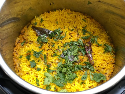Yellow rice topped with ghee, cilantro, and lime juice.