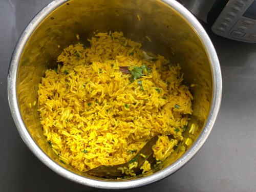 An instant pot with yellow rice fluffed after cooking.