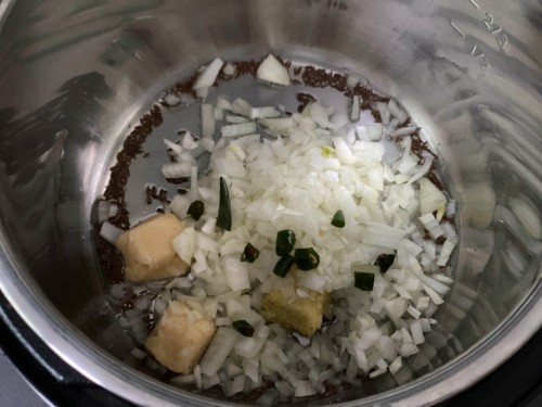 Adding onions, garlic, ginger and chilies to an Instant Pot.