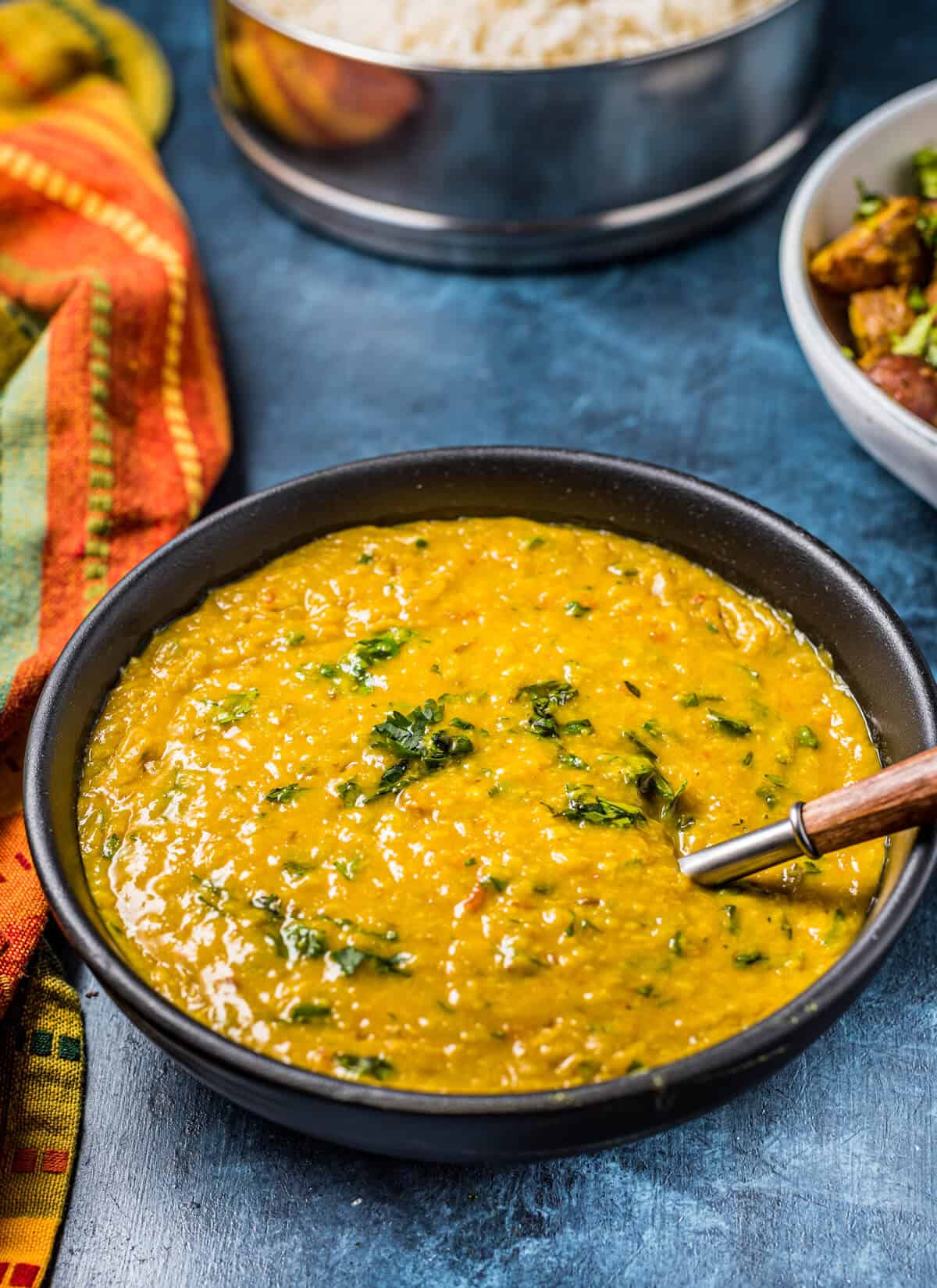 A bowl of Moong Dal on a blue table, garnished with cilantro.