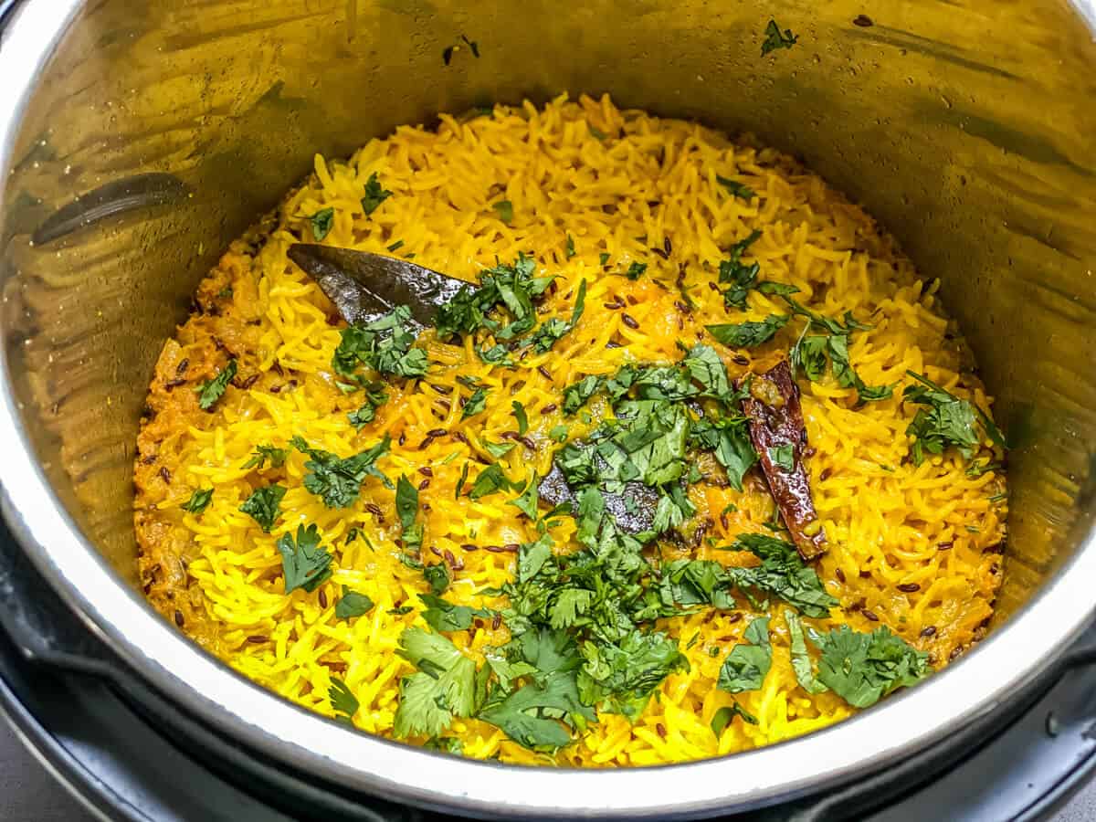 An instant pot with yellow rice, topped with fresh cilantro.
