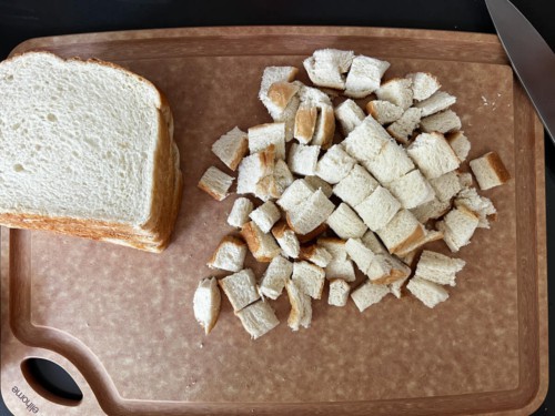 A brown cutting board with chopped bread.