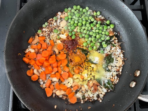 Veggies and seasoning added to the skillet.