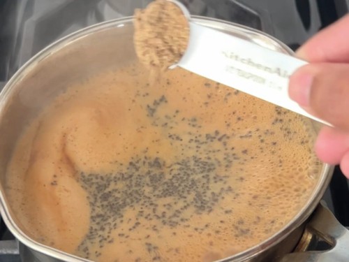 Adding chai masala powder to a boiled milk tea.