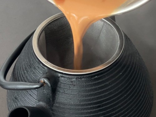 Straining chai masala into a pot.