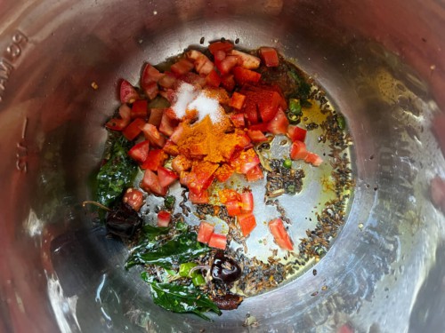 Adding tomatoes and aromatics to an Instant Pot with tempering seeds.