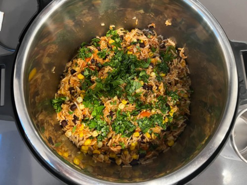Sprinkling cilantro on top of a rice mixture inside of an Instant Pot.