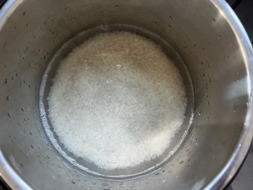 Adding rice to an Instant Pot with water in it.