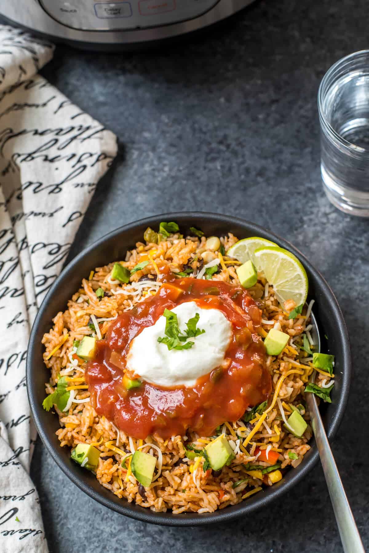 A bowl of Spanish rice topped with salsa and sour cream.