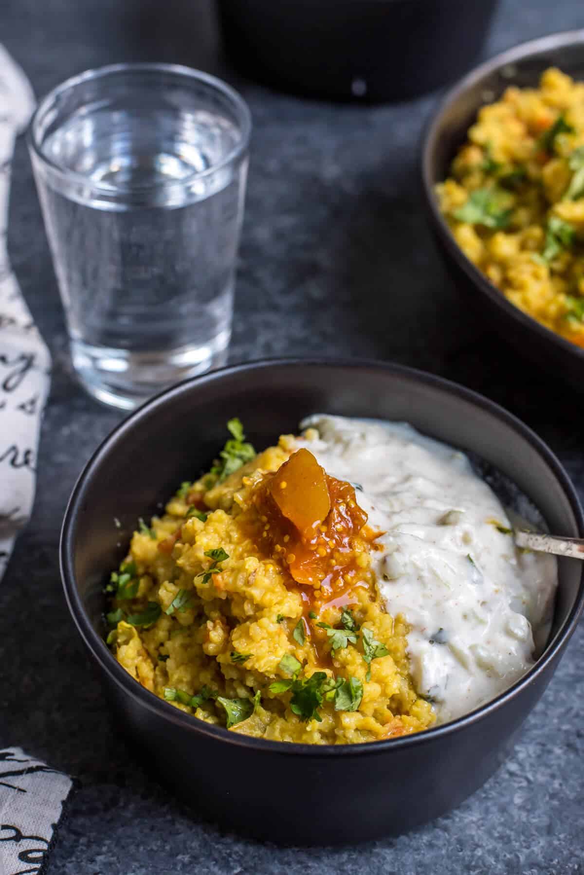 Masala khichdi in a bowl served with water on the side.