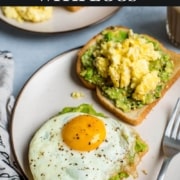 Two slices of avocado toast, topped with eggs: one scrambled and one fried.