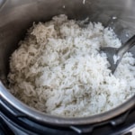 A top down photo of the Instant Pot with fresh cooked Jasmine rice and a silver spoon on the right side.