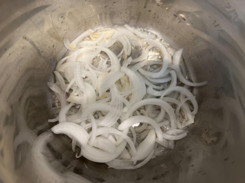 The inner chamber of the instant pot with onions.