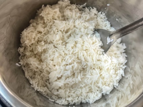 The inside of the Instant Pot with fluffy cooked Jasmine Rice and a silver spoon on the right.