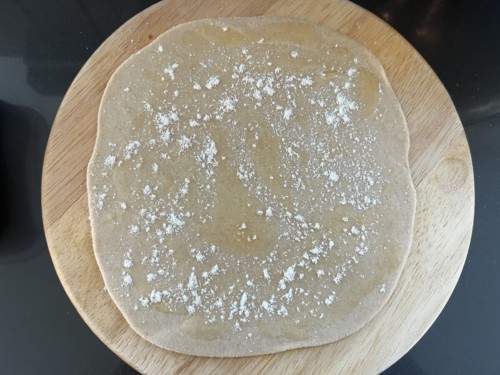 A wooden counter with a round of lacha dough sprinkled with flour.