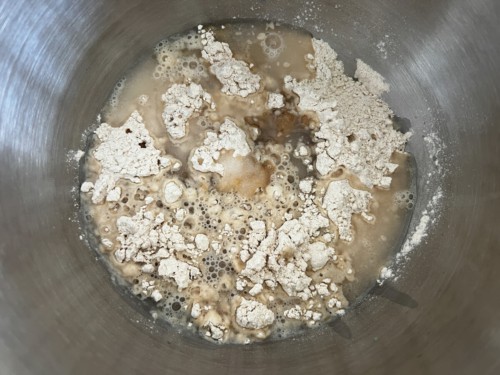 A silver mixing bowl with the ingredients for lachan paratha before being mixed into a dough.
