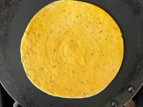 Uncooked masala paratha on a hot pan.