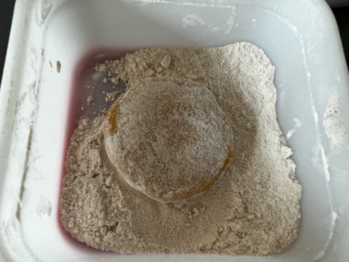 A ball of flattened dough in the whole wheat flour.