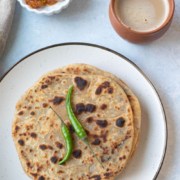 A stack of onion paratha garnished with chilies.