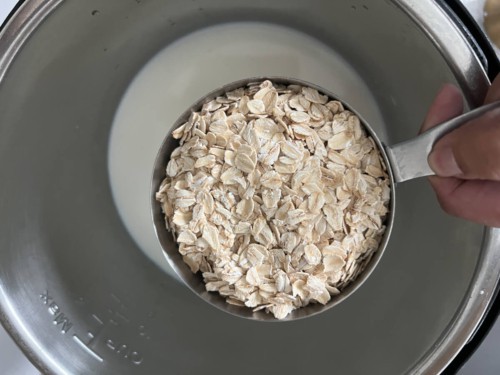 A measuring cup with oatmeal over the Instant Pot.