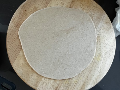 Rolling the paratha into a round shape.