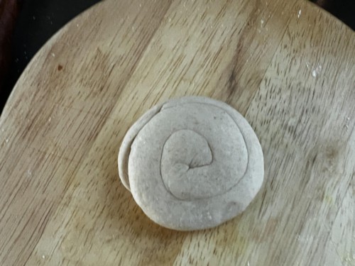 Flattening a dough disc for paratha.