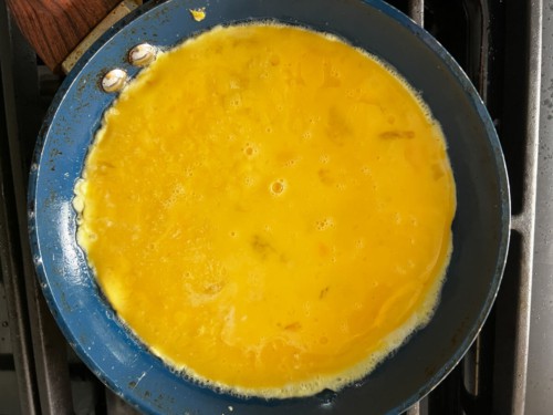 Eggs added to a non-stick skillet.