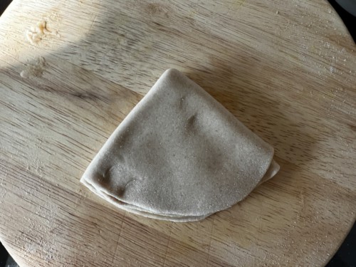 Folding dough in half twice to make a triangle.