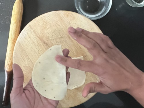 Dabbing the edges of a dough half circle with water.