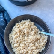 A bowl of brown rice with a spoon.