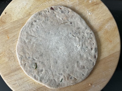 Rolling a stuffed paratha into a thin round.