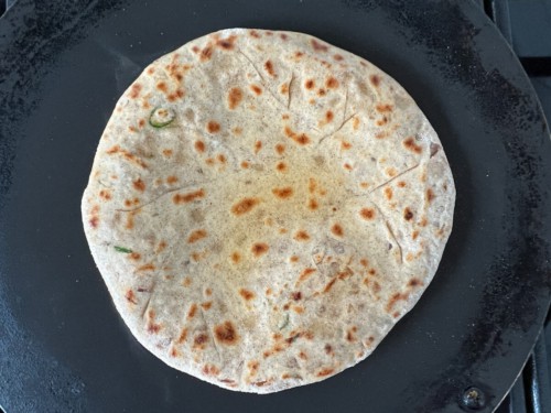 Turning over a paratha to cook on the other side.