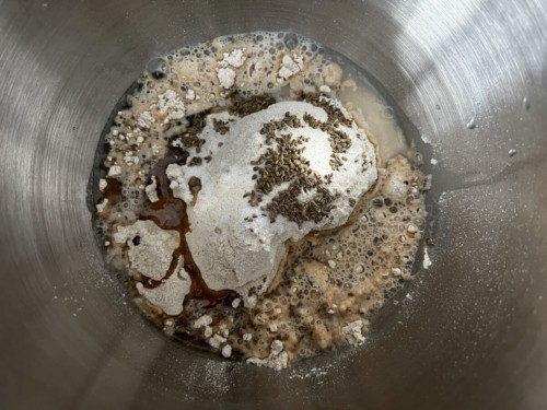 Adding together water, flour, and spices to make a paratha dough.