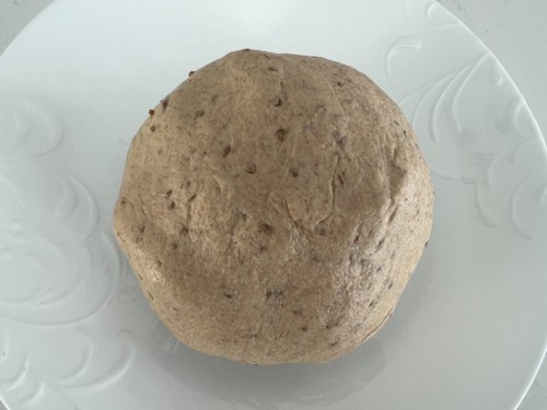 A ball of paratha dough on a white surface.
