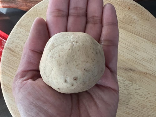 A hand holding a small amount of caraway seed paratha dough.