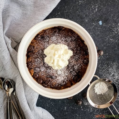 Chocolate bread pudding served in white bowls with whipped cream