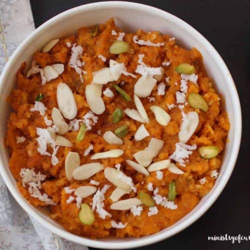 Pumpkin halwa topped with almonds and pistachios served in a white bowl