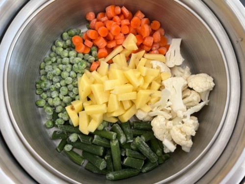 Frozen and chopped veggies in the Instant Pot: Carrots, peas, green beans, potatoes, and cauliflower.