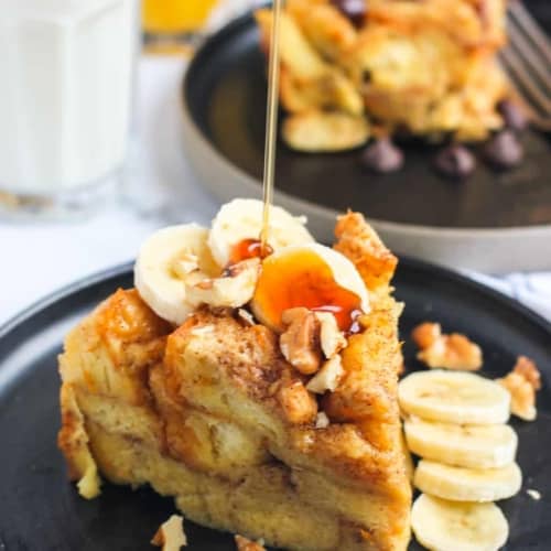 French toast bread pudding on a black plate drizzled with maple syrup