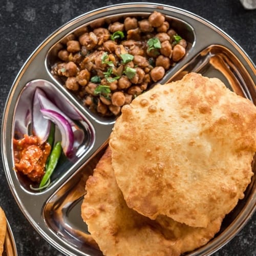 Bhatura served with kala chana and pickle, onions, and green chilly