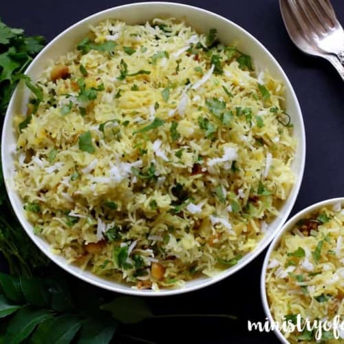 Cabbage rice served in two white bowls with curry and cilantro leaves on the side