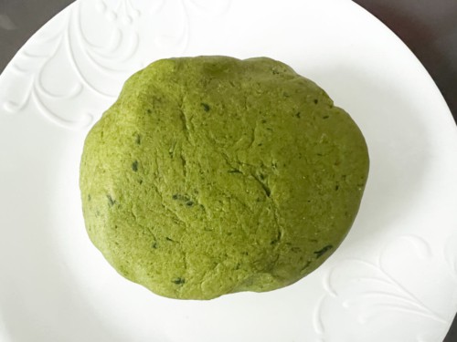 Rested palak paratha dough ball on a white background.