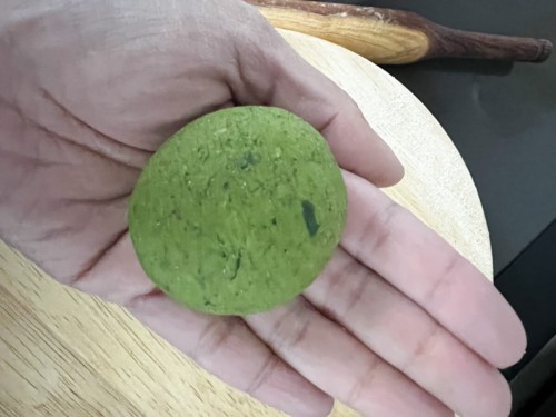 Hand with small ball of spinach paratha dough.