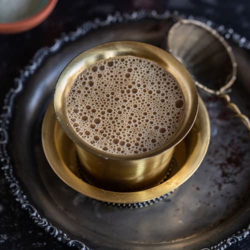 Filter coffee served in a brass tumbler and saucer set