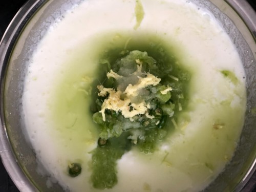 Yogurt, milk, grated cucumber, and ginger in a steel bowl